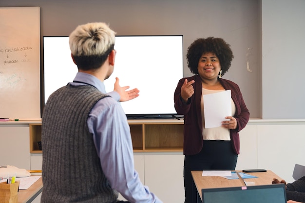 A photograph of a student giving a presentation to a panel of educators, showcasing their portfolio of work. The student appears confident and engaged, demonstrating their skills and knowledge in a practical setting.
