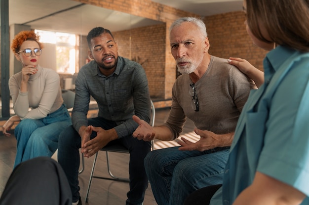 A diverse group of veterans sitting and smiling together during a group therapy session, facilitated by a healthcare professional.