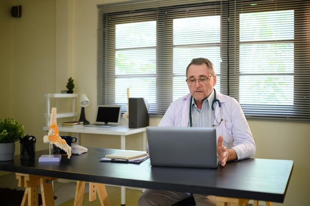 A veteran sitting comfortably in a modern doctor's office, engaged in a telehealth consultation with a healthcare provider on a laptop.