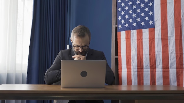 A US veteran is sitting at a desk, using a laptop to fill out an online application for healthcare benefits. The room is well-lit and organized, suggesting a focus on administrative tasks and accessing resources online.