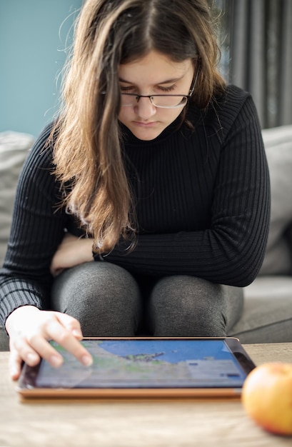 A student using a tablet with an adaptive learning app, showing personalized exercises and feedback. The interface is user-friendly and engaging, with colorful graphics and clear instructions.